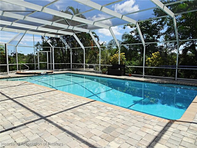 view of swimming pool with glass enclosure and a patio