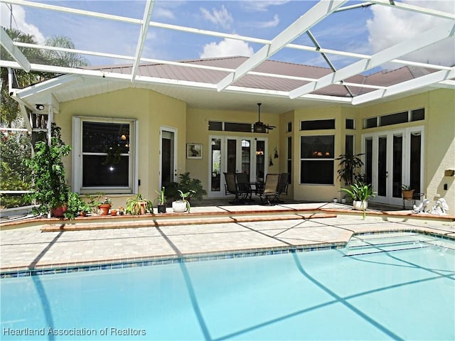 view of swimming pool with glass enclosure, ceiling fan, french doors, and a patio area