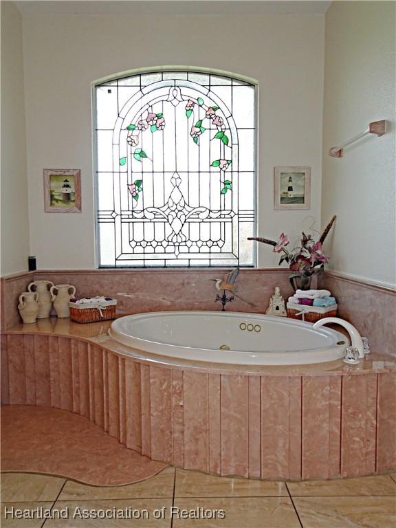 bathroom featuring tile patterned flooring and a relaxing tiled tub