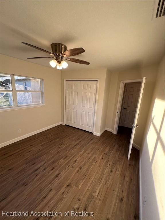unfurnished bedroom featuring ceiling fan, dark hardwood / wood-style flooring, and a closet