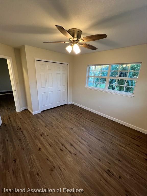 unfurnished bedroom featuring ceiling fan, dark hardwood / wood-style floors, and a closet