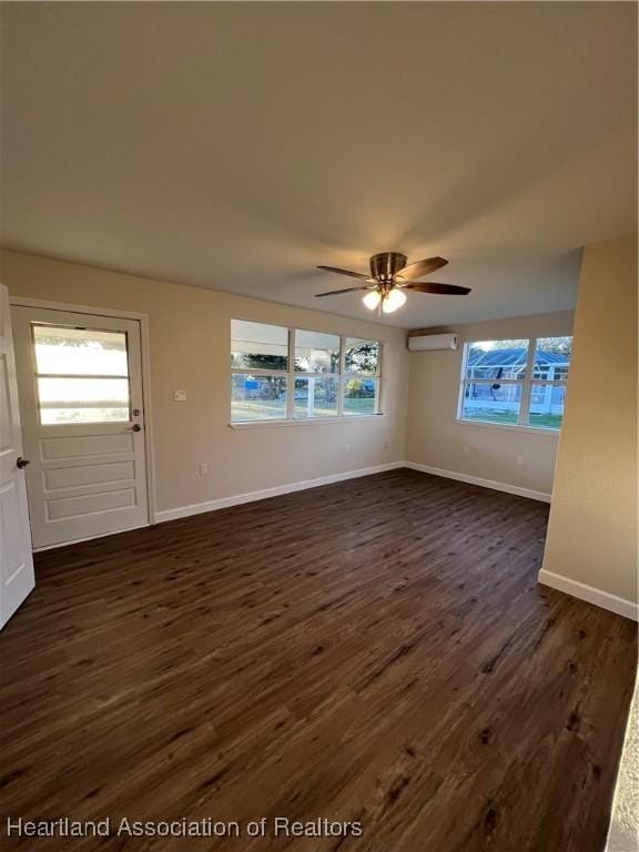 unfurnished living room with a wealth of natural light, dark wood-type flooring, a wall mounted air conditioner, and ceiling fan