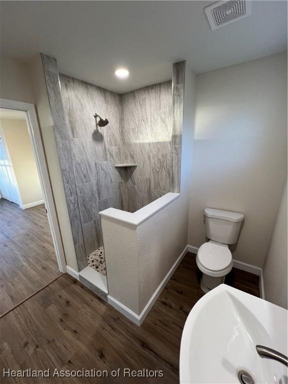 bathroom with hardwood / wood-style flooring, toilet, sink, and a shower