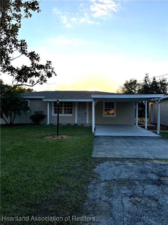 view of front of property featuring a lawn and a carport