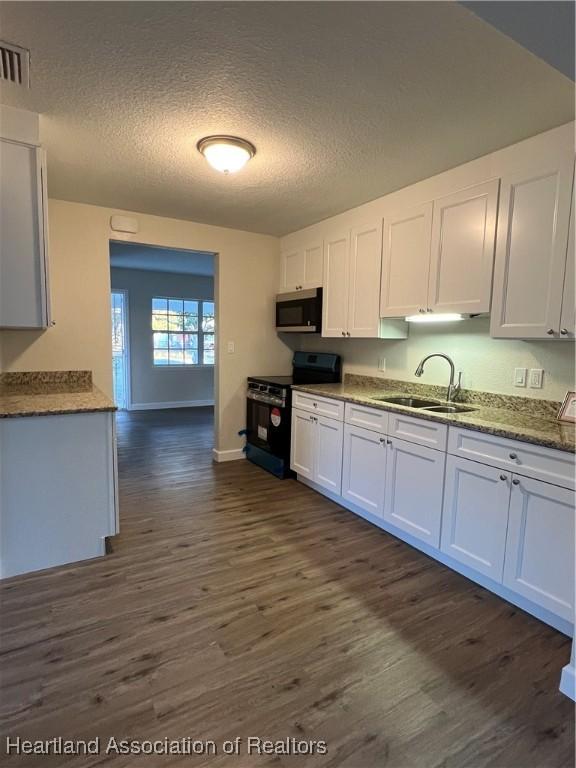 kitchen with sink, white cabinetry, range with electric stovetop, a textured ceiling, and dark hardwood / wood-style flooring