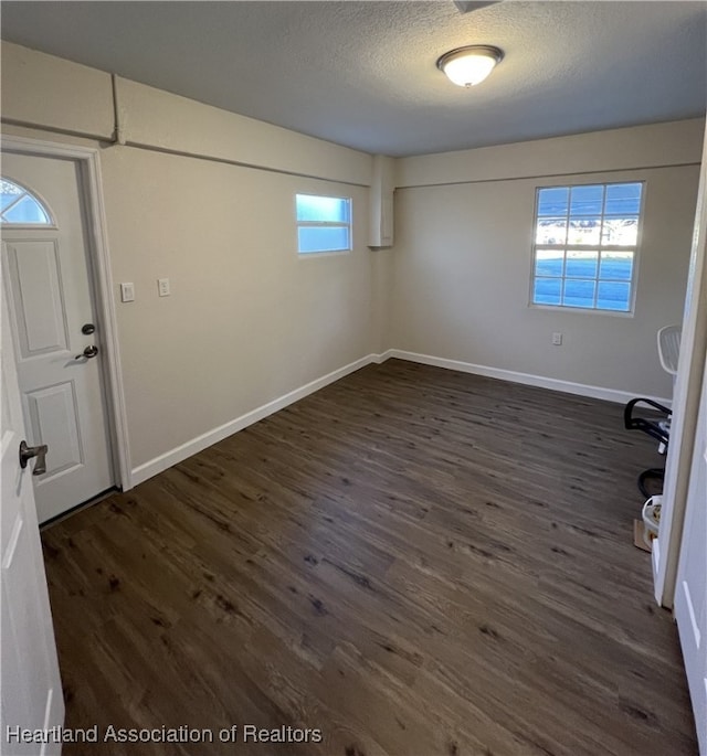 basement featuring plenty of natural light, dark hardwood / wood-style floors, and a textured ceiling