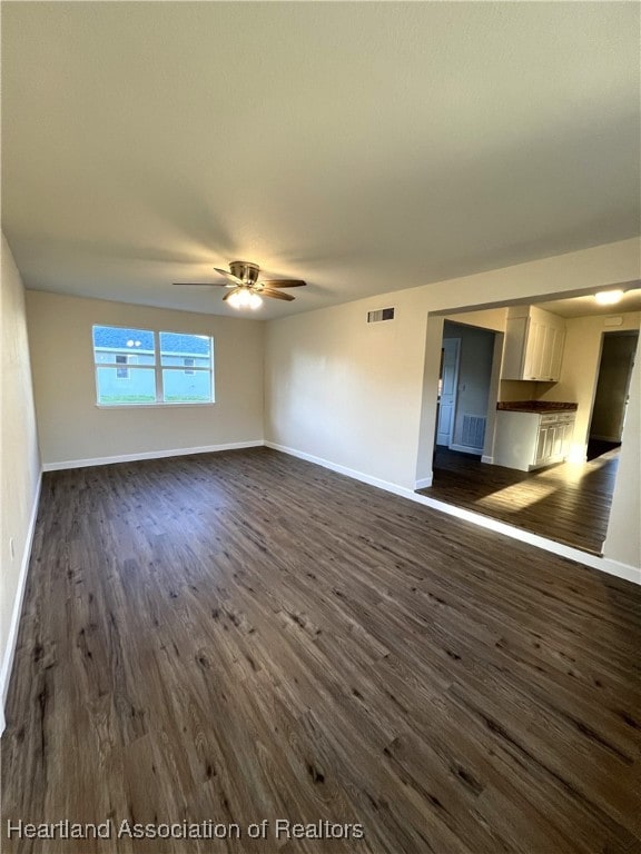 unfurnished living room featuring ceiling fan and dark hardwood / wood-style flooring