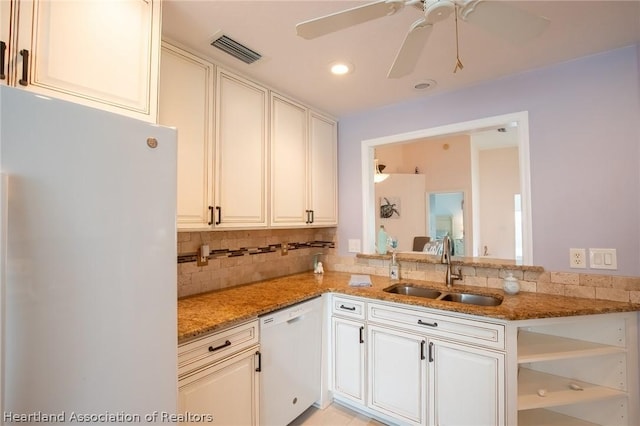 kitchen featuring light stone countertops, white appliances, ceiling fan, and sink