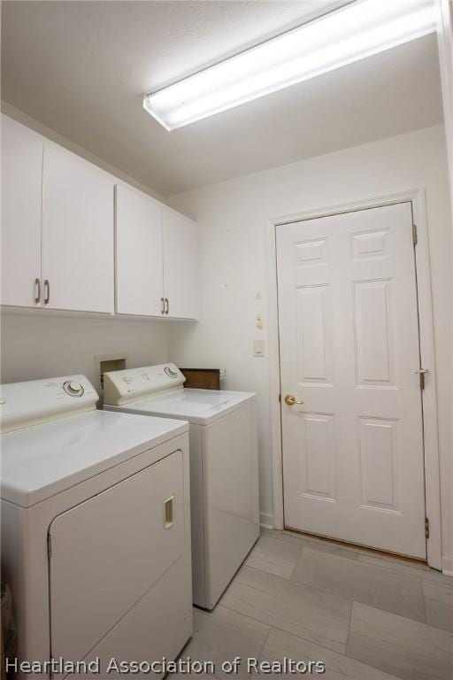 laundry area with separate washer and dryer and cabinets