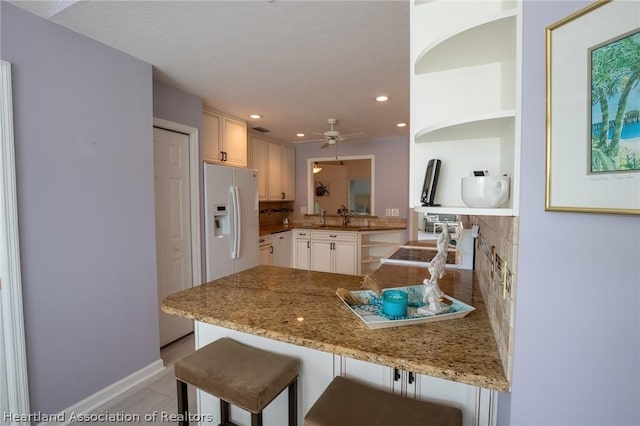 kitchen with a kitchen breakfast bar, kitchen peninsula, white cabinetry, and tasteful backsplash