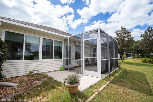 view of home's exterior with glass enclosure, a patio area, and a yard