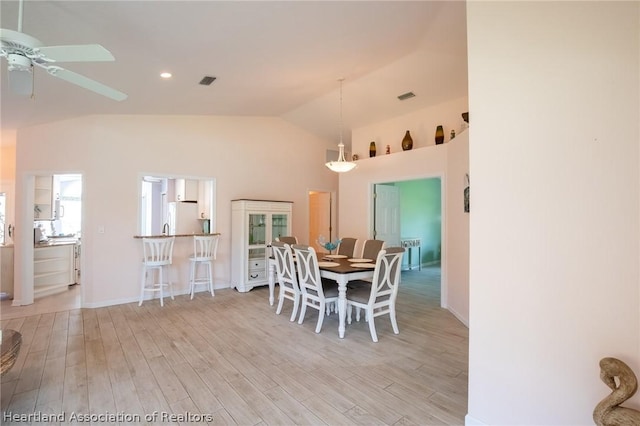 dining space with ceiling fan, light hardwood / wood-style flooring, and vaulted ceiling