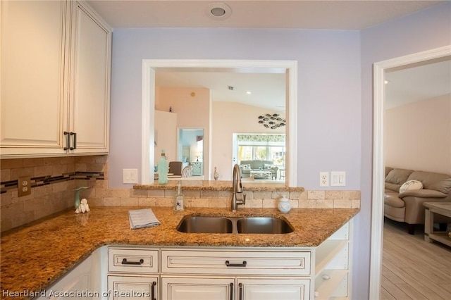 kitchen featuring decorative backsplash, sink, white cabinets, and dark stone counters