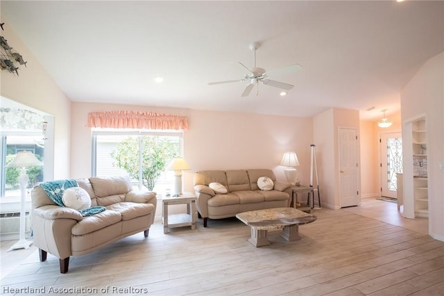 living room featuring ceiling fan, light hardwood / wood-style flooring, and vaulted ceiling