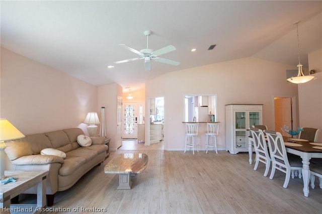 living room with light hardwood / wood-style flooring, vaulted ceiling, and ceiling fan