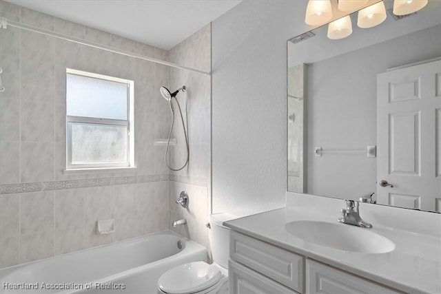 full bathroom with vanity, tiled shower / bath combo, and toilet