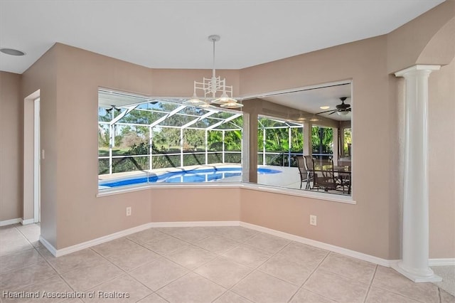 unfurnished dining area featuring tile patterned floors, ceiling fan, a healthy amount of sunlight, and decorative columns