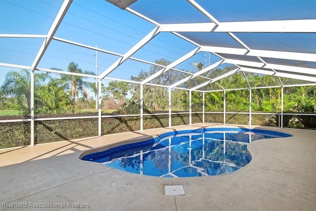 view of pool with glass enclosure and a patio area