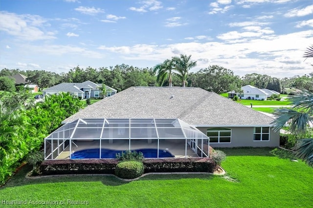 rear view of house featuring a lawn and a lanai