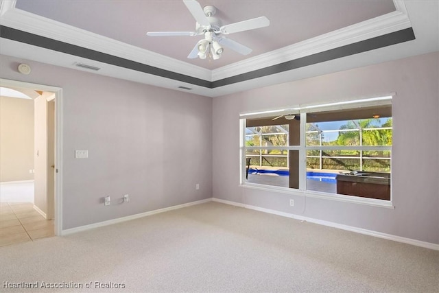 carpeted empty room featuring ceiling fan, a raised ceiling, and ornamental molding