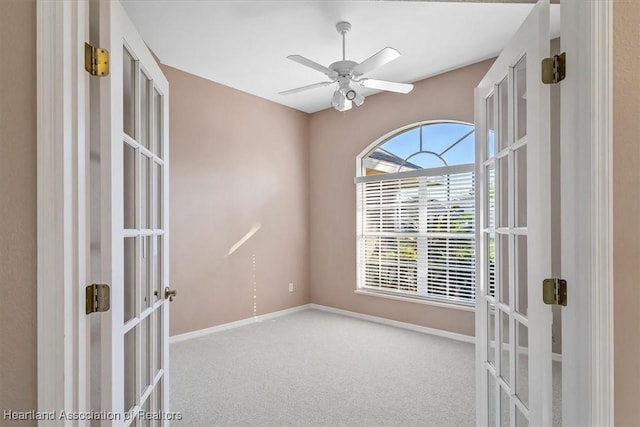 carpeted spare room with ceiling fan and french doors