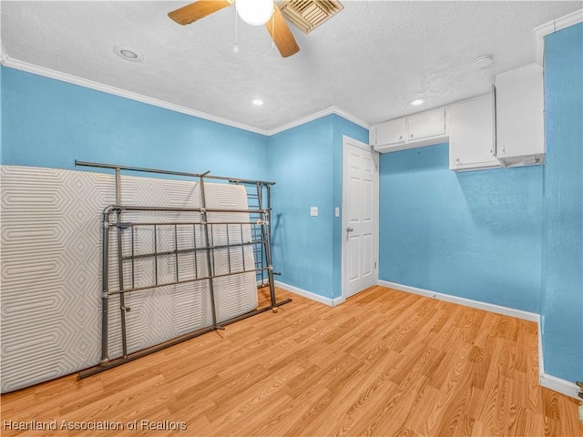 bedroom with baseboards, light wood finished floors, visible vents, and crown molding