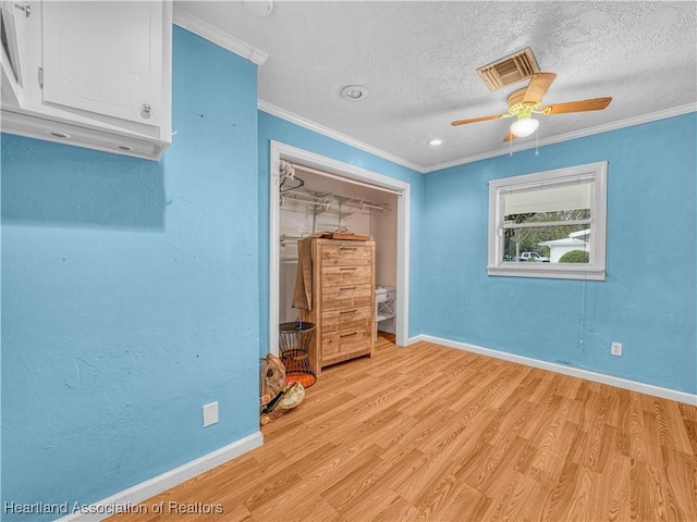 unfurnished bedroom with visible vents, ornamental molding, a textured ceiling, light wood-type flooring, and baseboards