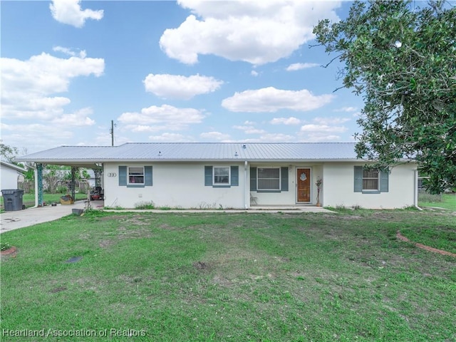 ranch-style home with stucco siding, a front yard, metal roof, an attached carport, and driveway