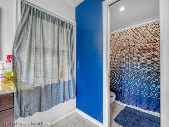 full bath with toilet, tile patterned flooring, and baseboards