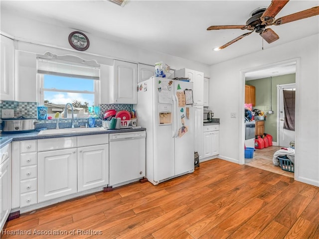 kitchen with decorative backsplash, light wood-style floors, white cabinets, a sink, and white appliances