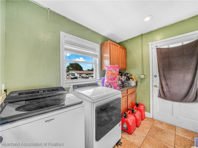 washroom with light tile patterned flooring, washing machine and dryer, and cabinet space