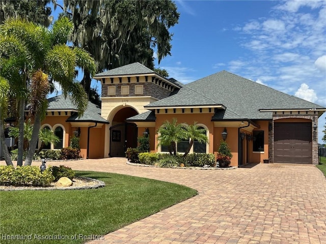 2230 Lake Ariana Blvd, Auburndale, FL 33823 - mediterranean / spanish-style home with decorative driveway, an attached garage, a front lawn, stucco siding, and stone siding