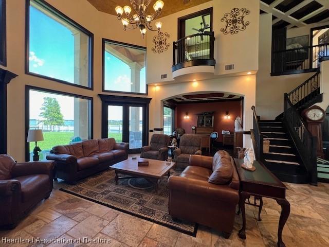 2230 Lake Ariana Blvd, Auburndale, FL 33823 - living area featuring a high ceiling, a chandelier, stairs, beam ceiling, and stone tile floors