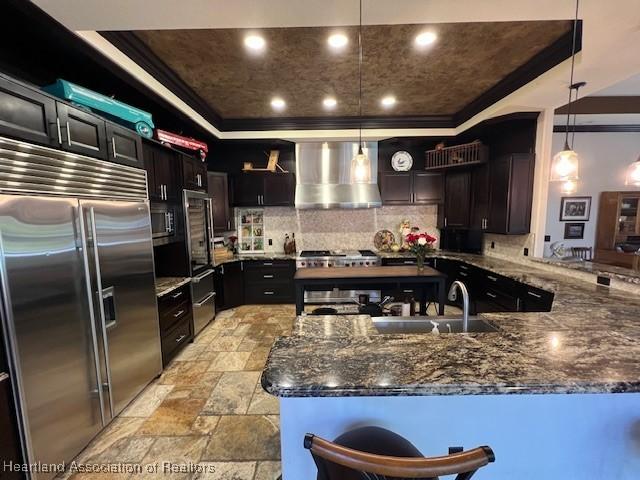 2230 Lake Ariana Blvd, Auburndale, FL 33823 - kitchen featuring built in refrigerator, a raised ceiling, wall chimney exhaust hood, tasteful backsplash, and ornamental molding