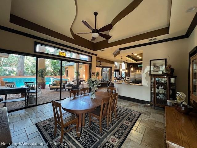 2230 Lake Ariana Blvd, Auburndale, FL 33823 - dining space featuring stone tile floors, a ceiling fan, a raised ceiling, ornamental molding, and a towering ceiling