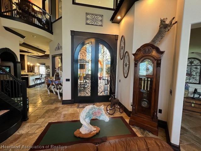 2230 Lake Ariana Blvd, Auburndale, FL 33823 - entrance foyer with stone tile flooring, a high ceiling, french doors, and stairway