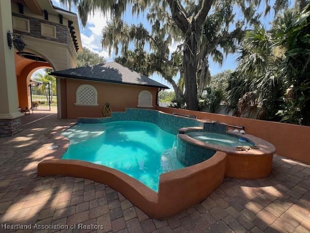2230 Lake Ariana Blvd, Auburndale, FL 33823 - view of swimming pool featuring a pool with connected hot tub, a gate, and a patio area