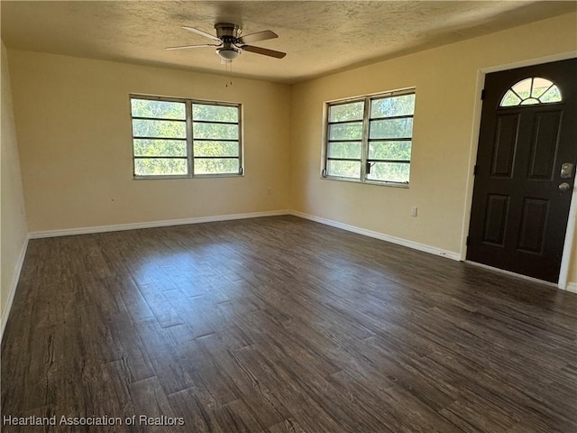 foyer entrance with dark wood-style flooring, ceiling fan, baseboards, and a textured ceiling