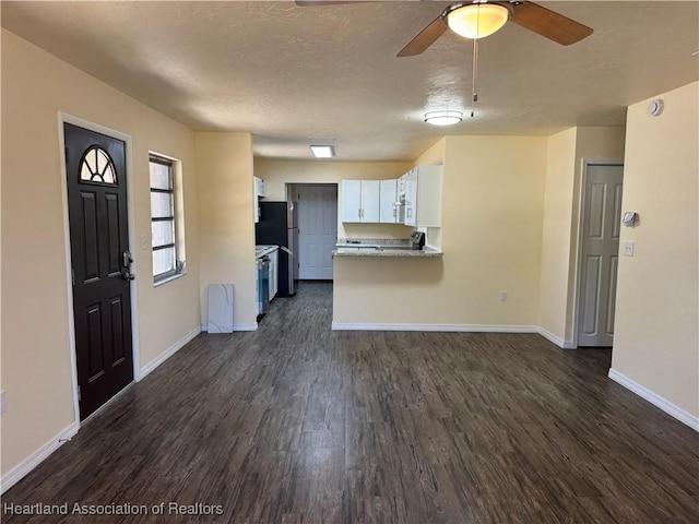 unfurnished living room featuring a ceiling fan, baseboards, and dark wood finished floors