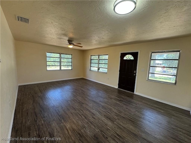 foyer with a textured ceiling, ceiling fan, dark wood-style floors, and visible vents
