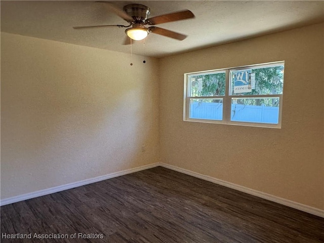 spare room with a textured wall, ceiling fan, baseboards, and dark wood finished floors