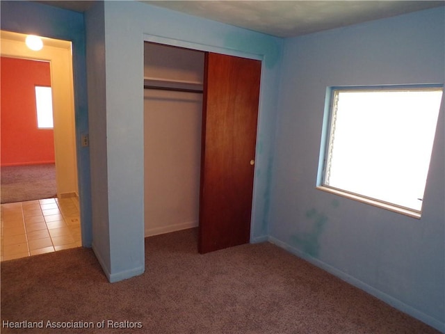 unfurnished bedroom with multiple windows, a closet, and carpet