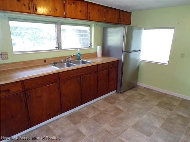 kitchen featuring stainless steel refrigerator, sink, and a healthy amount of sunlight