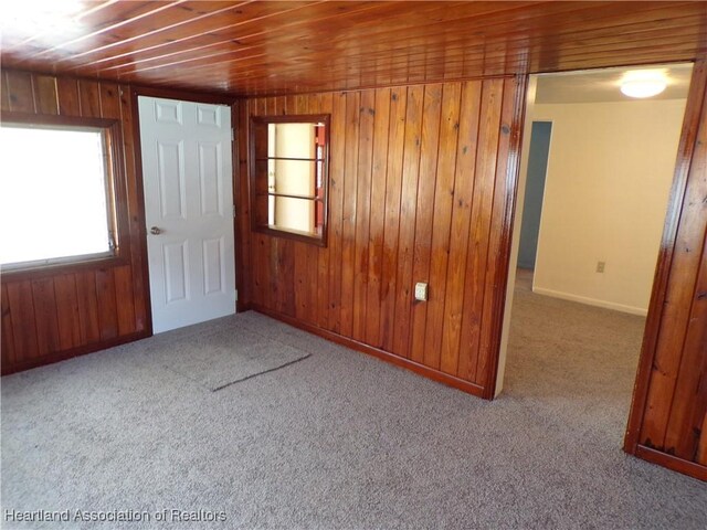 carpeted empty room with wooden walls and wood ceiling