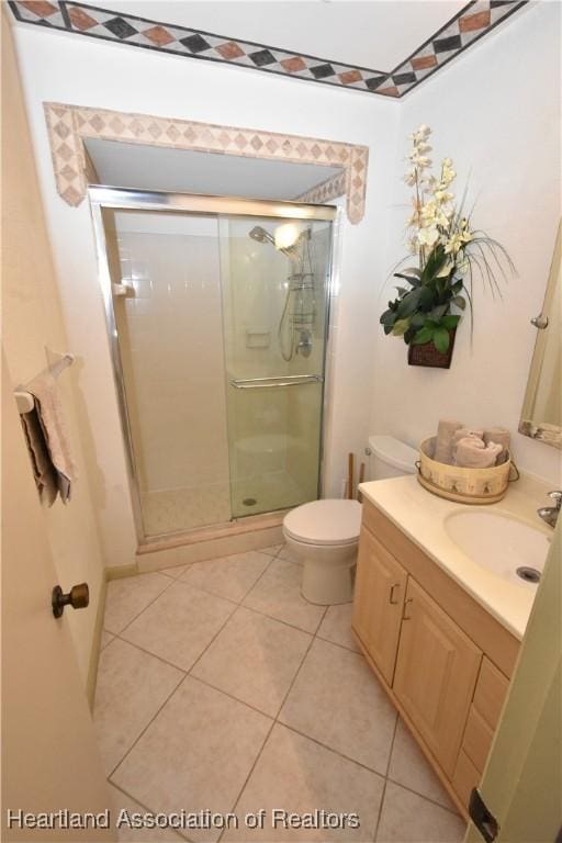 bathroom featuring tile patterned flooring, vanity, toilet, and an enclosed shower