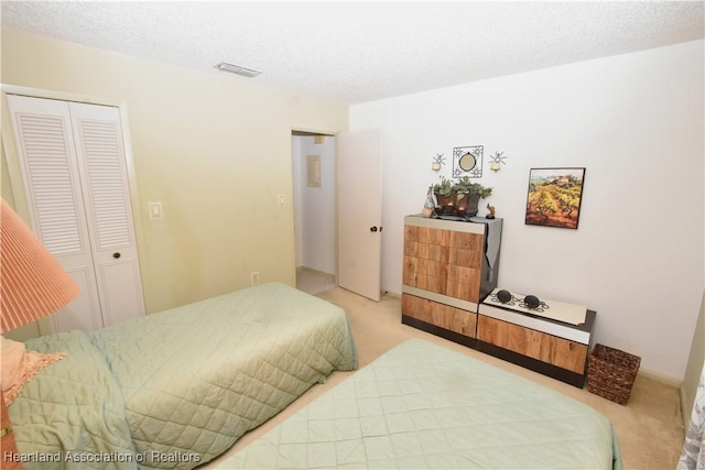 bedroom featuring a textured ceiling, light carpet, and a closet