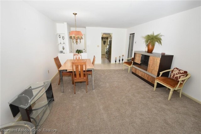 carpeted dining area with a chandelier