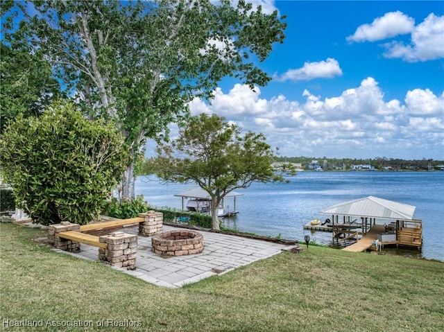 view of dock with an outdoor fire pit, a water view, a lawn, and a patio