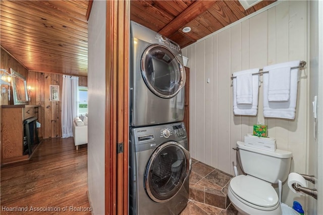 washroom with laundry area, wood walls, wood ceiling, stacked washer / drying machine, and dark wood-style floors