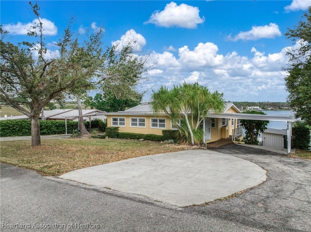 ranch-style home featuring a front lawn, aphalt driveway, and an attached carport